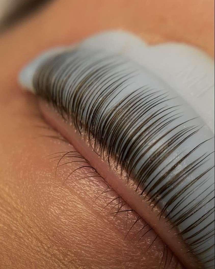 Close-up of an eye with a silicone pad used during a lash lift, showing lifted and separated upper eyelashes.